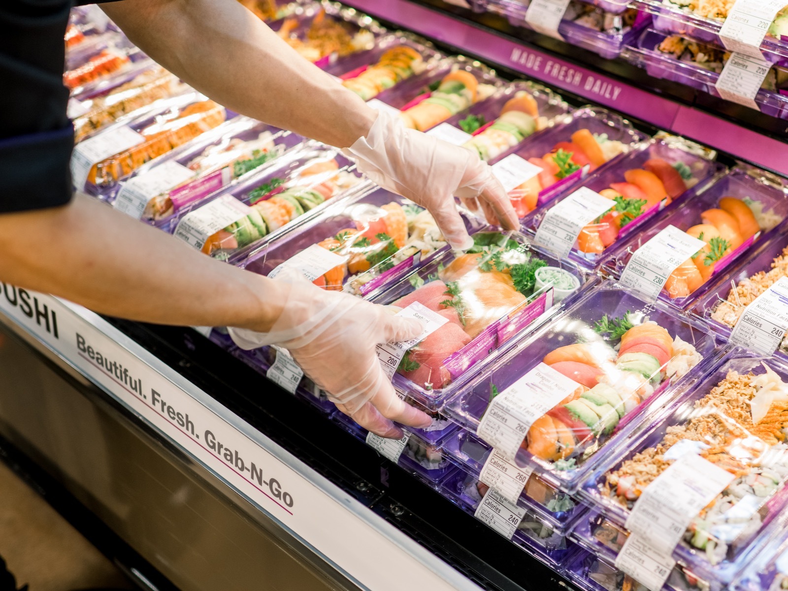 A worker placing pre-packaged sushi for display